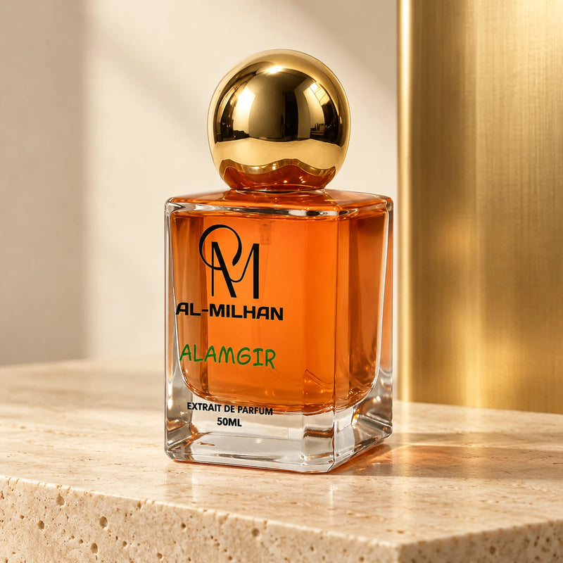 Alamgir bottle with orange liquid, green lettering and a spherical gold cap on pale limestone beside a gold panel.