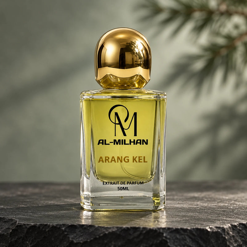 Arang Kel bottle with yellow liquid, gold lettering and a spherical gold cap on dark stone, with blurred green branches behind it.