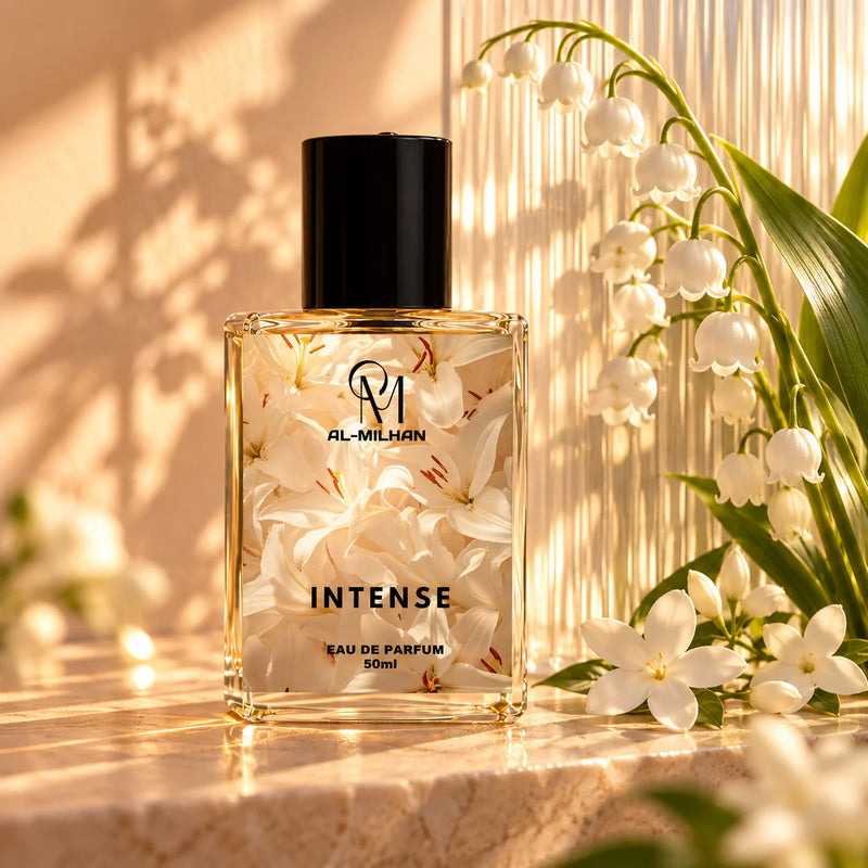 Intense bottle with its white-lily label beside arching white flowers and ribbed translucent glass in warm amber light.