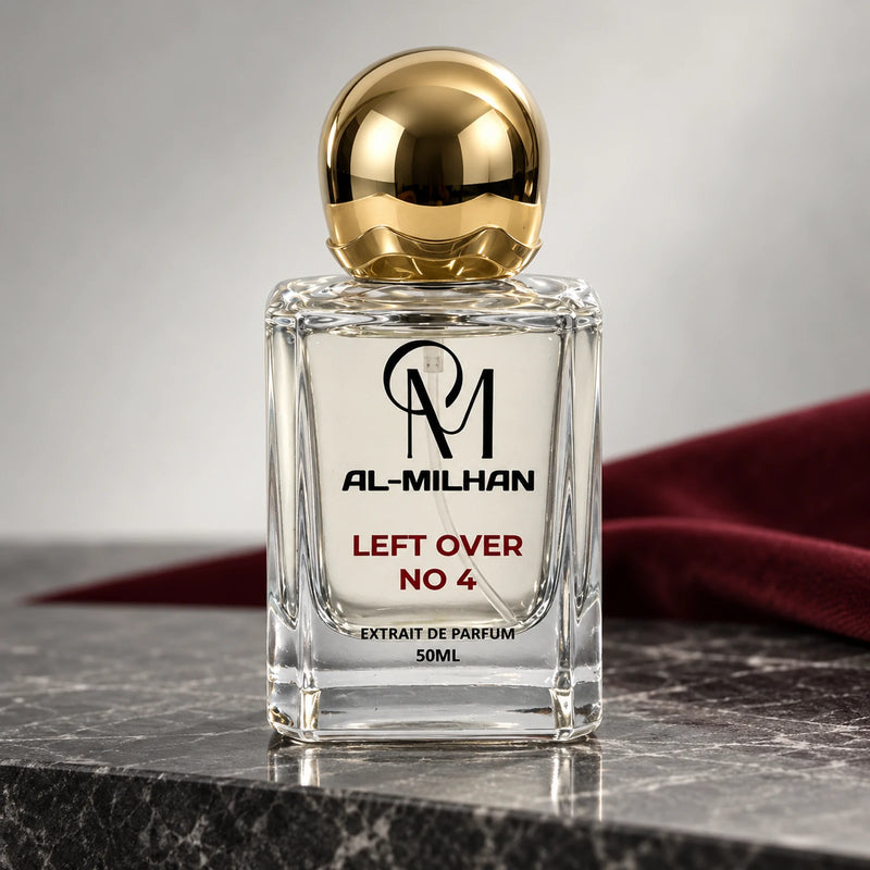 Left Over No 4 bottle with clear liquid, red lettering and a spherical gold cap on dark marble beside burgundy fabric.