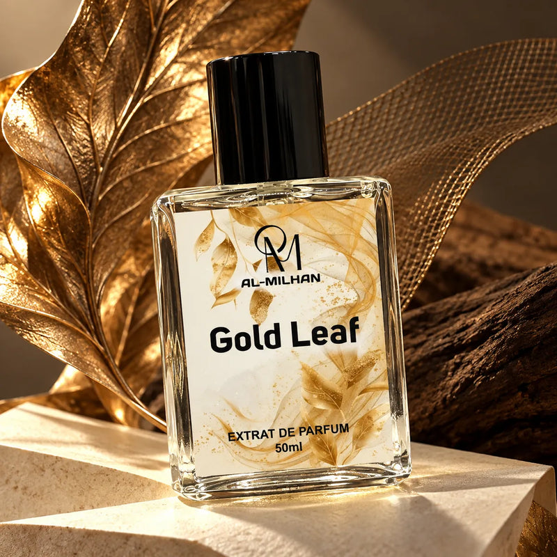 Gold Leaf perfume bottle by Al Milhan with clear liquid and its gold leaf label beside bronze leaf sculpture and ivory stone.