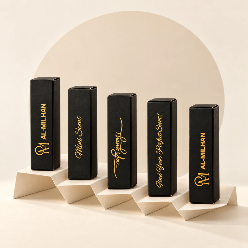 Five slim black and gold Al Milhan mini-scent tester boxes on an ivory folded-paper stand, against a simple beige background with a soft sand circle. Choose five perfume testers, 5 ml each.